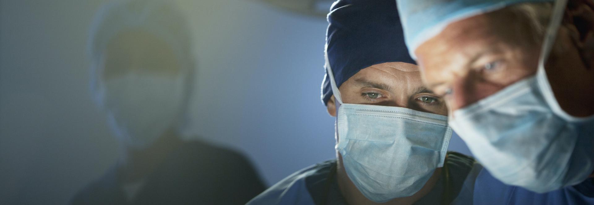 OP-Situation: Nahaufnahme von zwei männlichen Unfallchirurgen am Operationstisch 