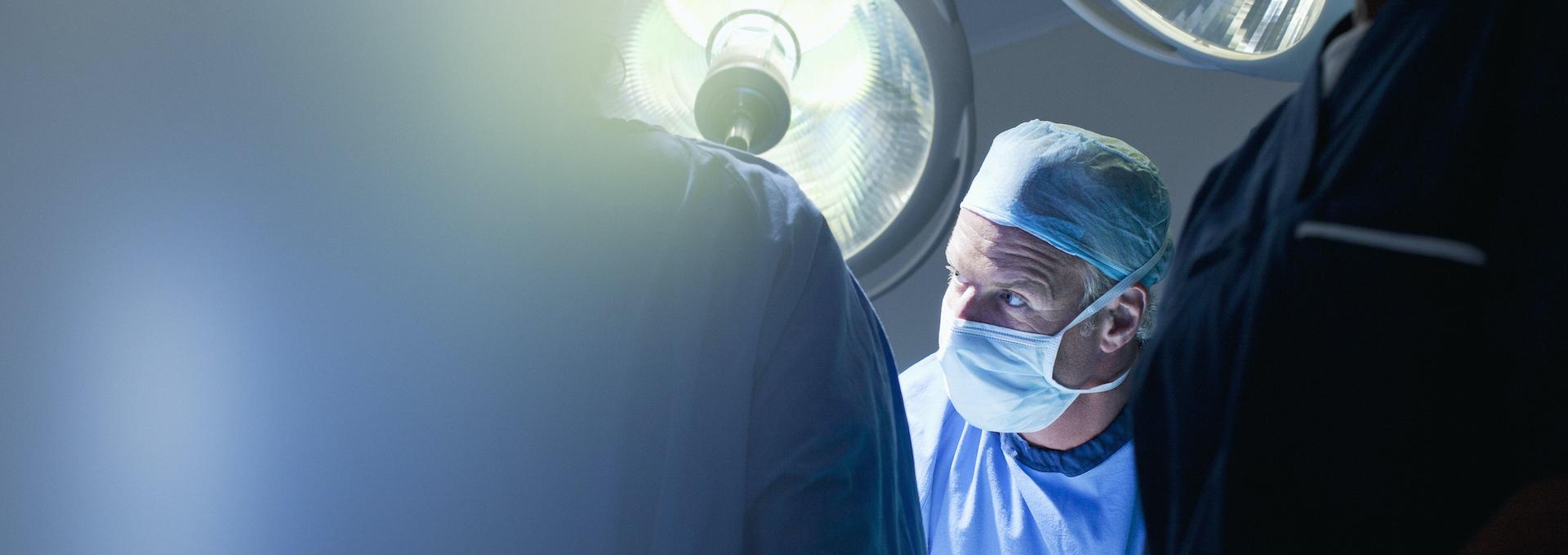 Symbolbild Traumaversorgung: Unfallchirurg in OP-Kleidung mit weiteren OP-Mitarbeitern am Operationstisch